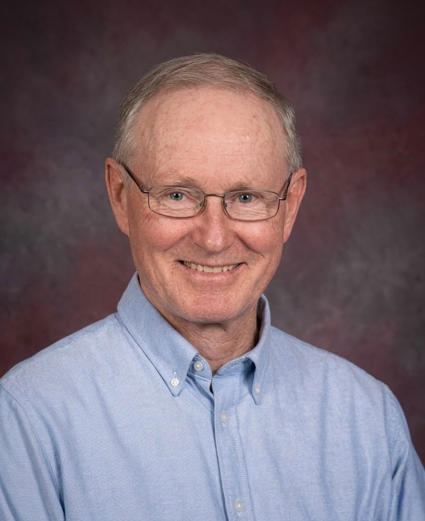 Older smiling man with light blue shirt