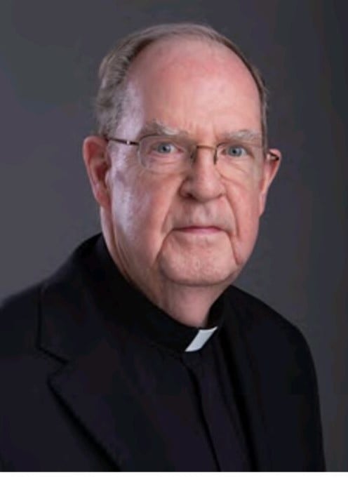 A smiling older priest with piercing blue-grey eyes and smiling