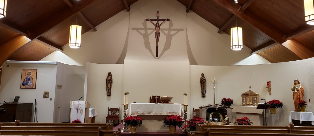 A front view of the Church with poinsettias and nativity scene, altar is draped in white
