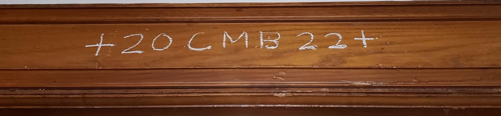 a brown door lintel with +20 CMB 22+ written on it in white chalk