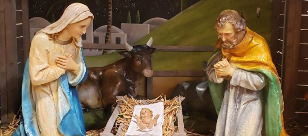 Young Mother Mary and Joseph look down lovingly at Baby Jesus in Manger