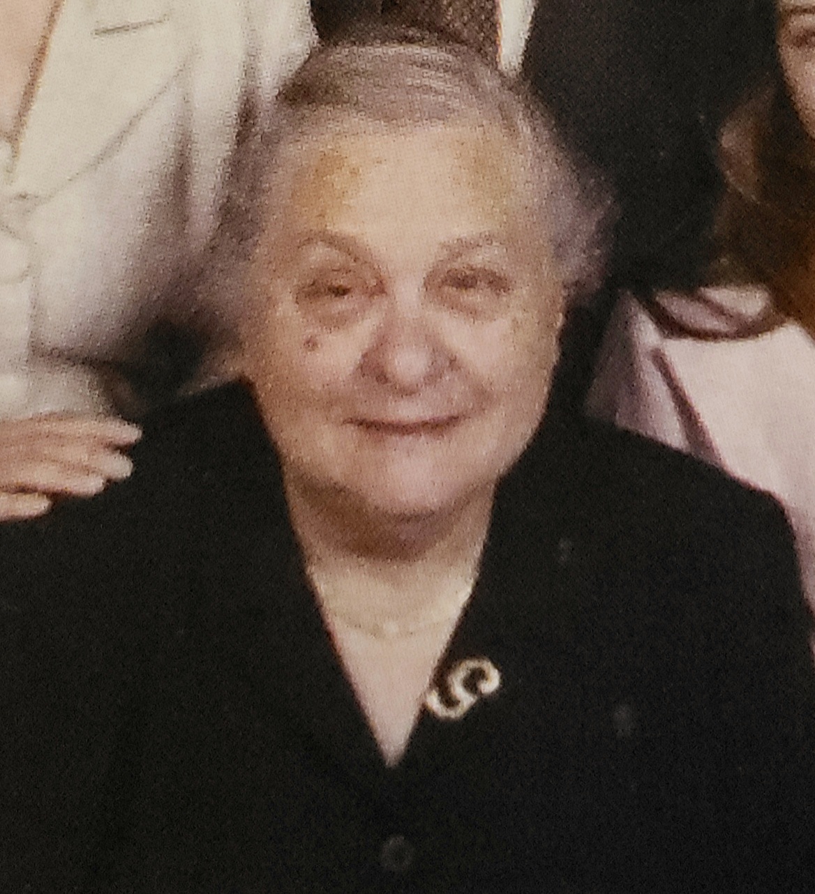 An older woman with grey hair and a plump face with a gentle smile